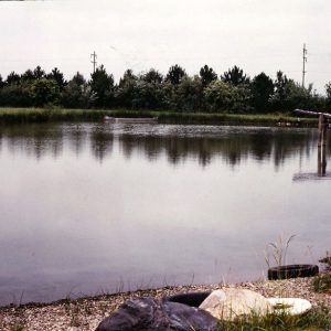 00-00-0000 Unidentified pond with canoe on it and pines in background-website