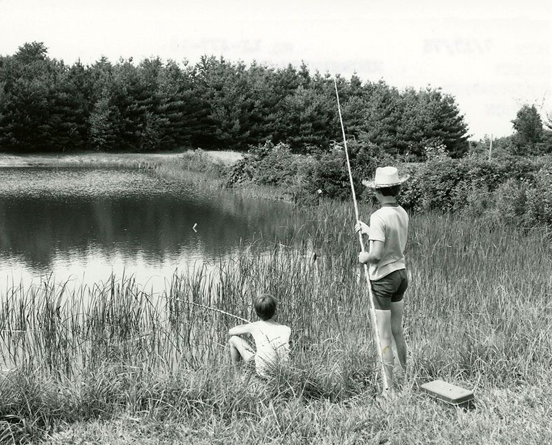 July 15, 1975. Edward Stewart and Todd Mills fishing for bass and bluegill on the 4H camp property at Rural Life Center
p srcset=