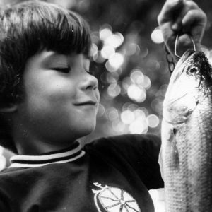 Boy holding and looking at a fish .Photo by Robert Mills