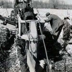 Man in betwwen ditch digging machine & tractor. Photo by Robert Mills