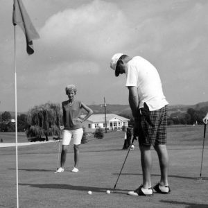 Man putting on a green. Two others look on .Photo by Robert Mills