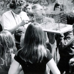 Man with group of students gathered around a cage with a critter. Photo by Robert Mills