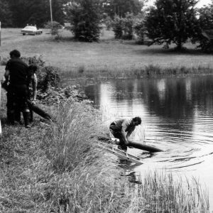 Three men pumping water from pond to truck .Photo by Robert Mills