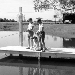 Two boys standing on pier fishing. Dog with them .Photo by Robert Mills