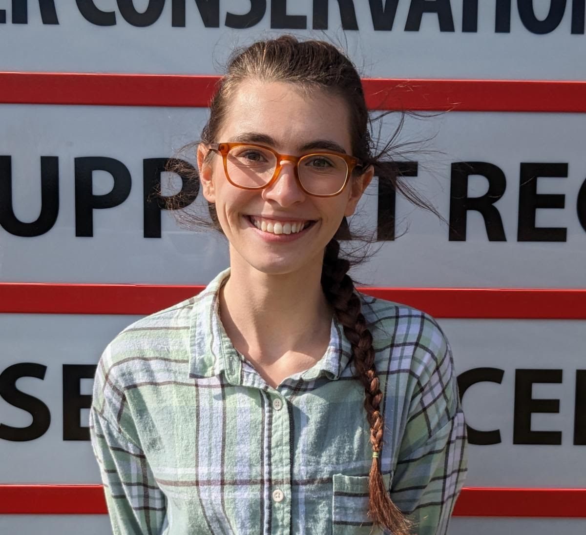 Zoe posed in front of a red and white sign smiling