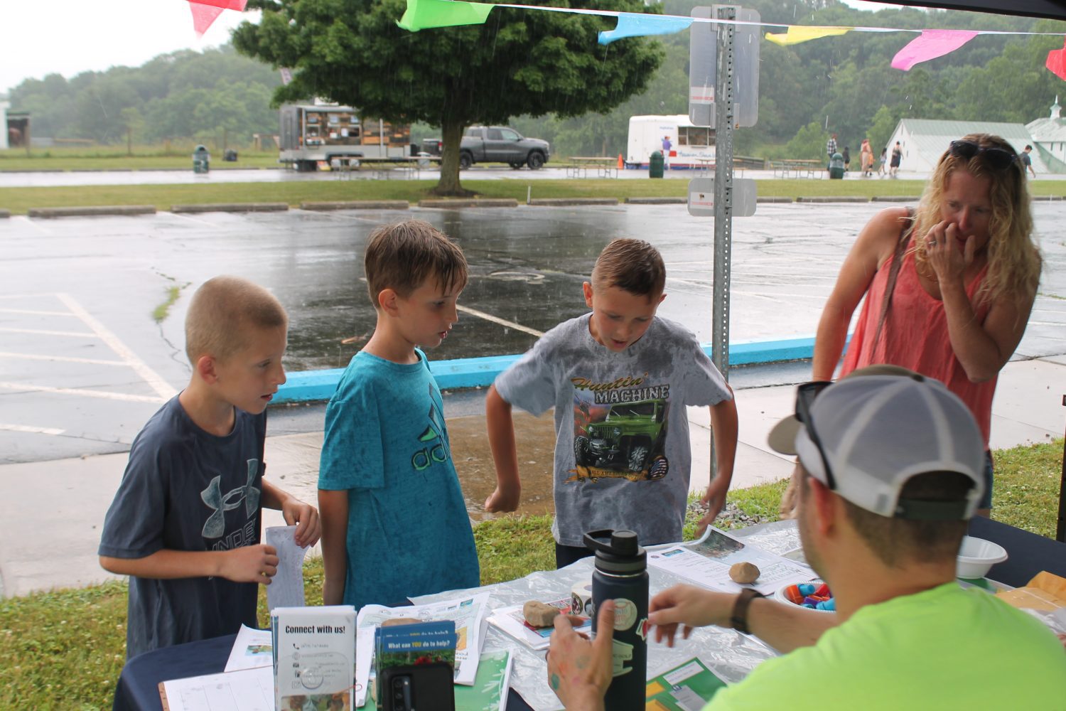 3 boys and their mom getting hand stamps and stickers at a vendor booth 
