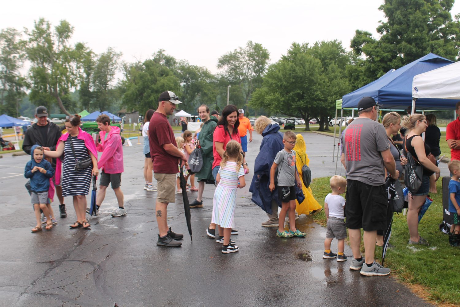 Families in line at a vendor booth getting rained on but smiling 