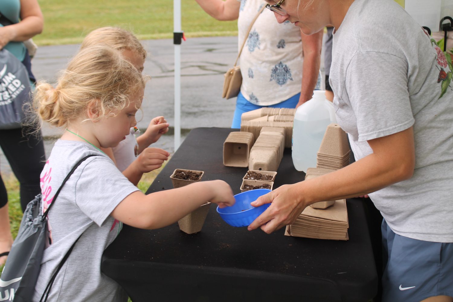 Close-up of two little girls sowing seeds at a vendor booth 