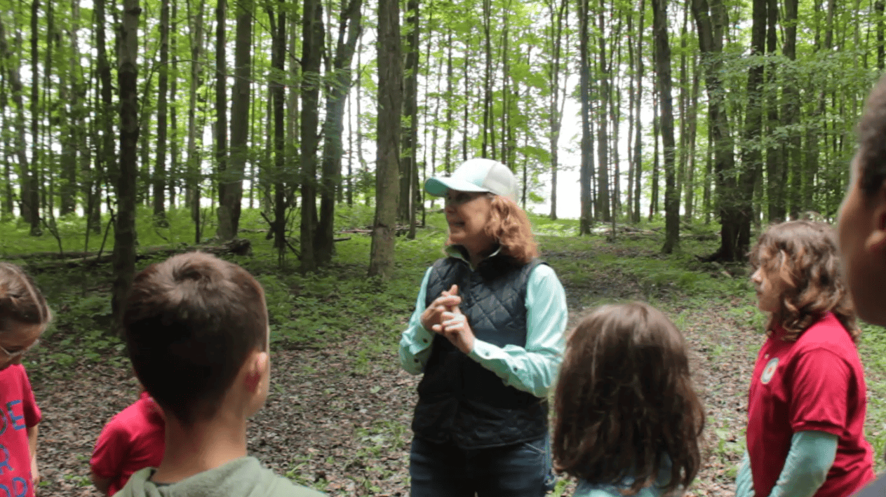 Pam in the woods explaining activities to the students.