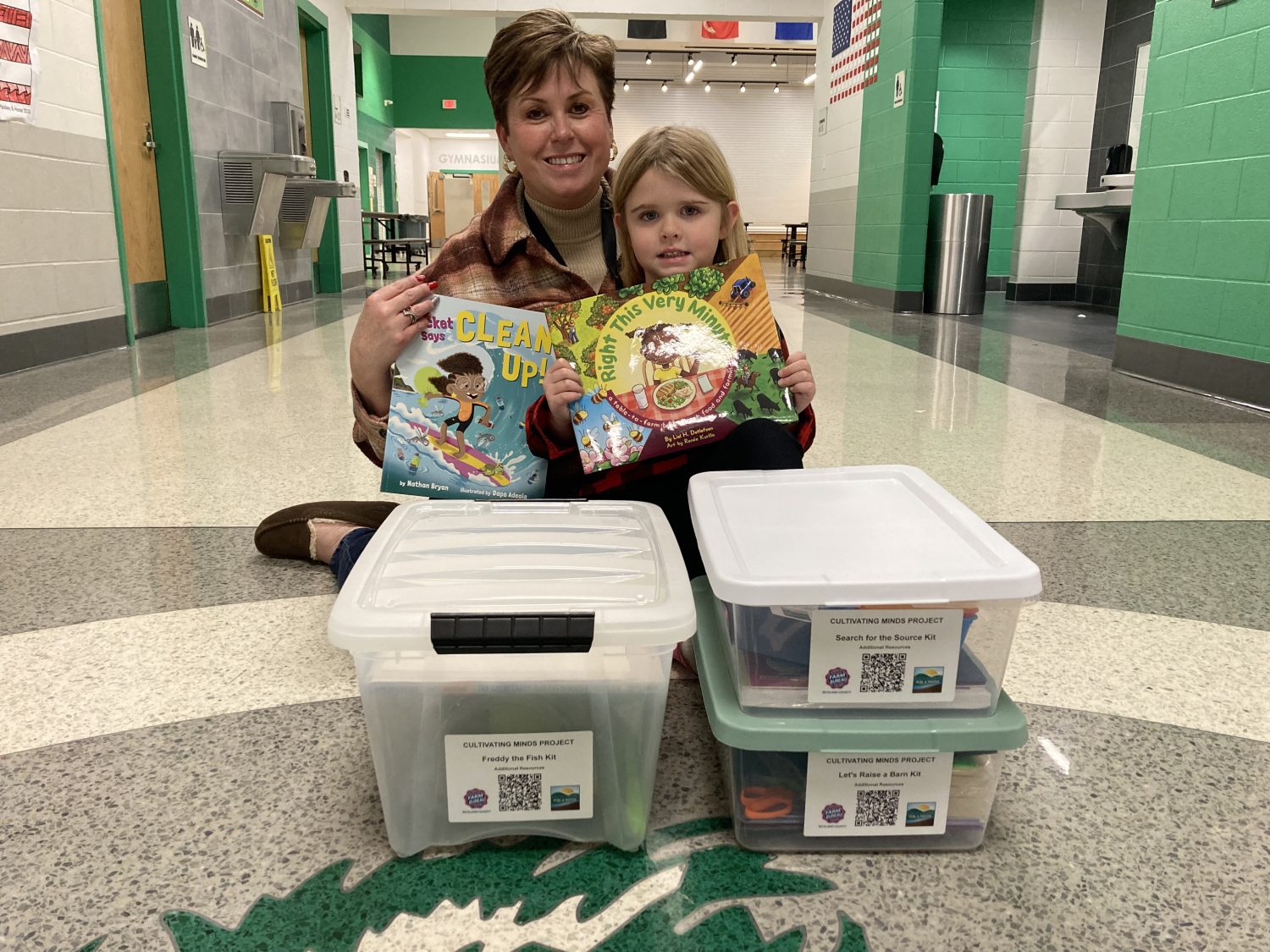 Principal Libby Nickoli and a student posed with the education kits. They're smiling for the camera holding books.