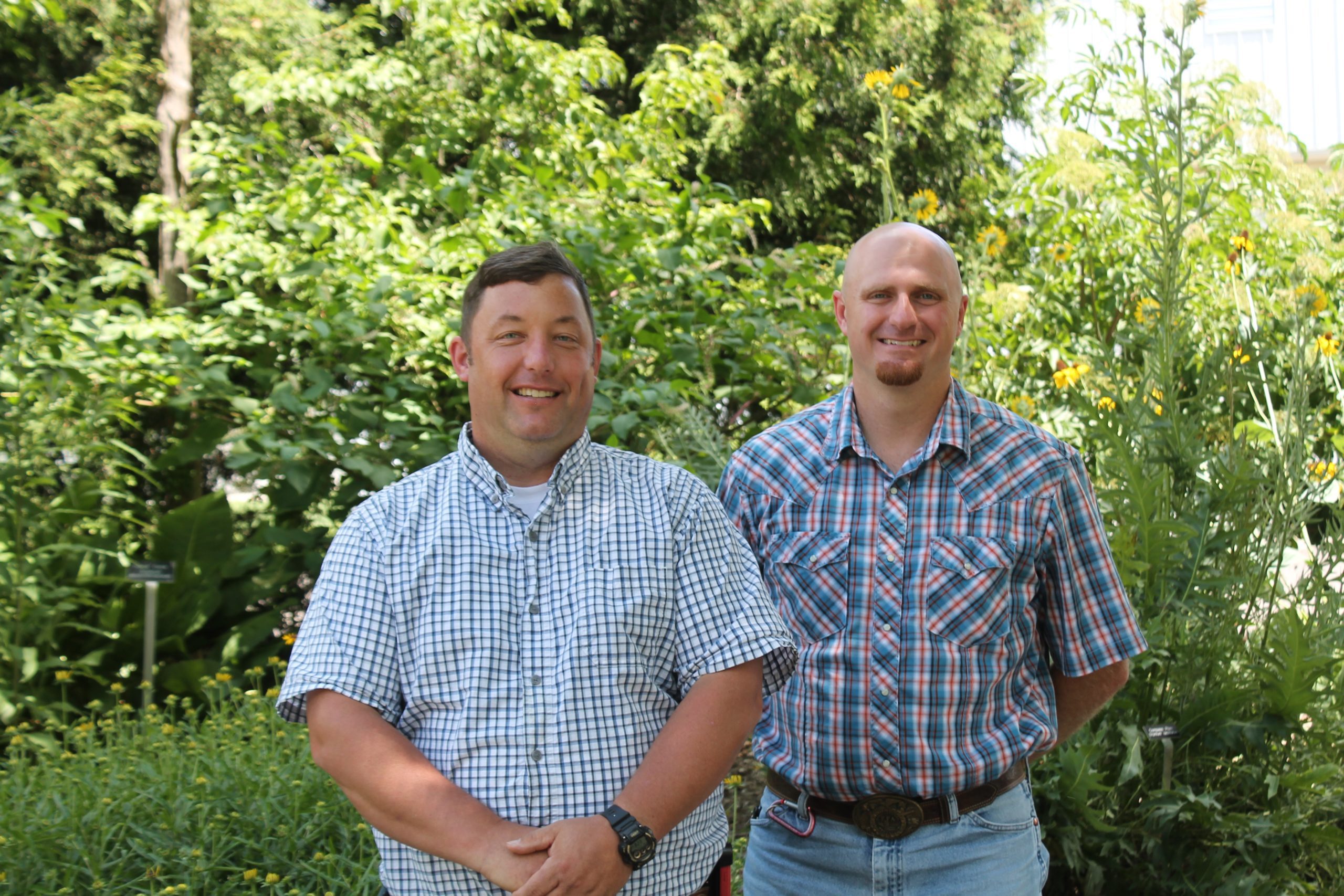 Jason Ruhl and Jordan Miller standing in front of green vegetation smiling for the camera.