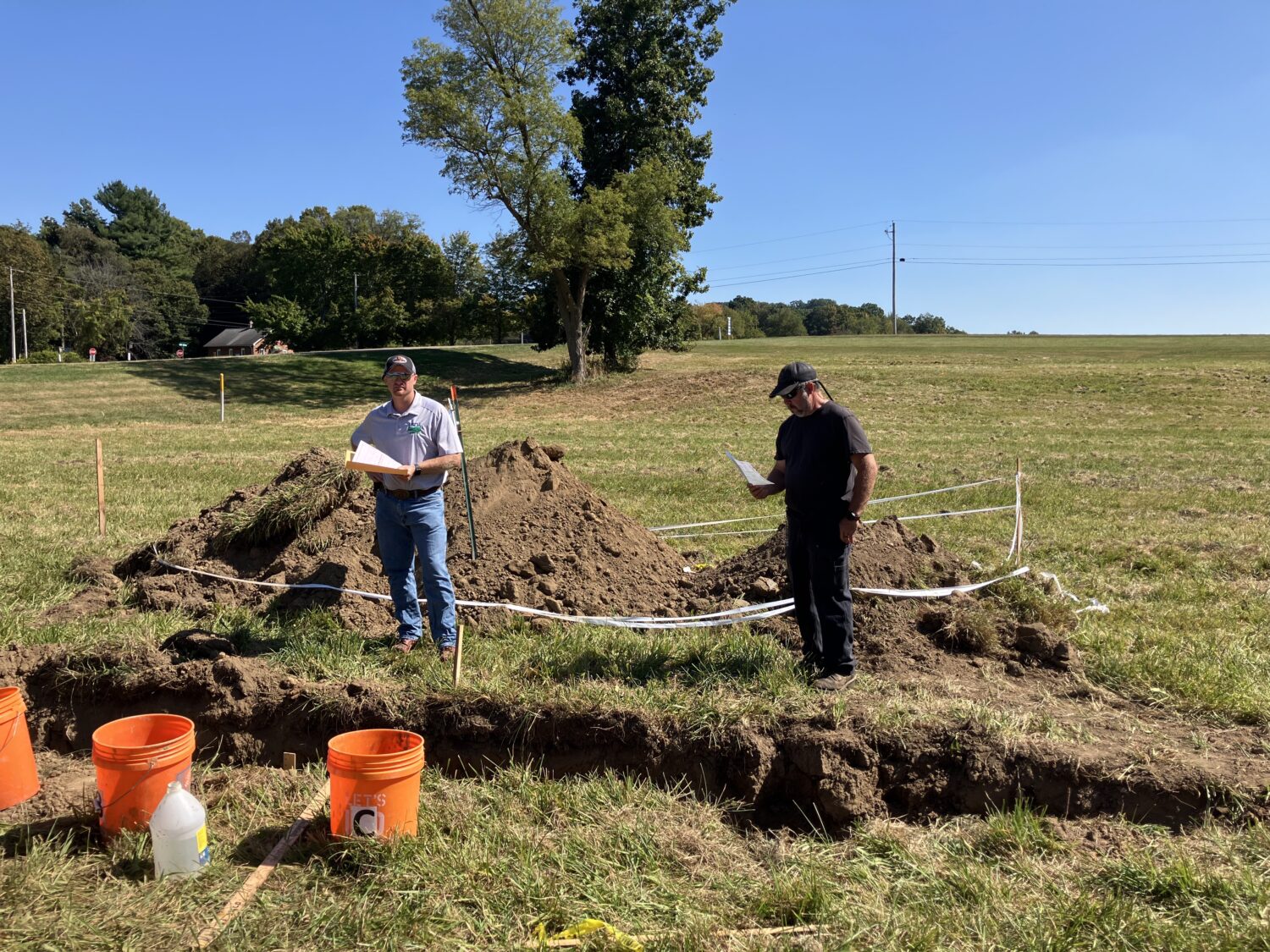 Matt and Jordan standing behind a soil pit reading the results.