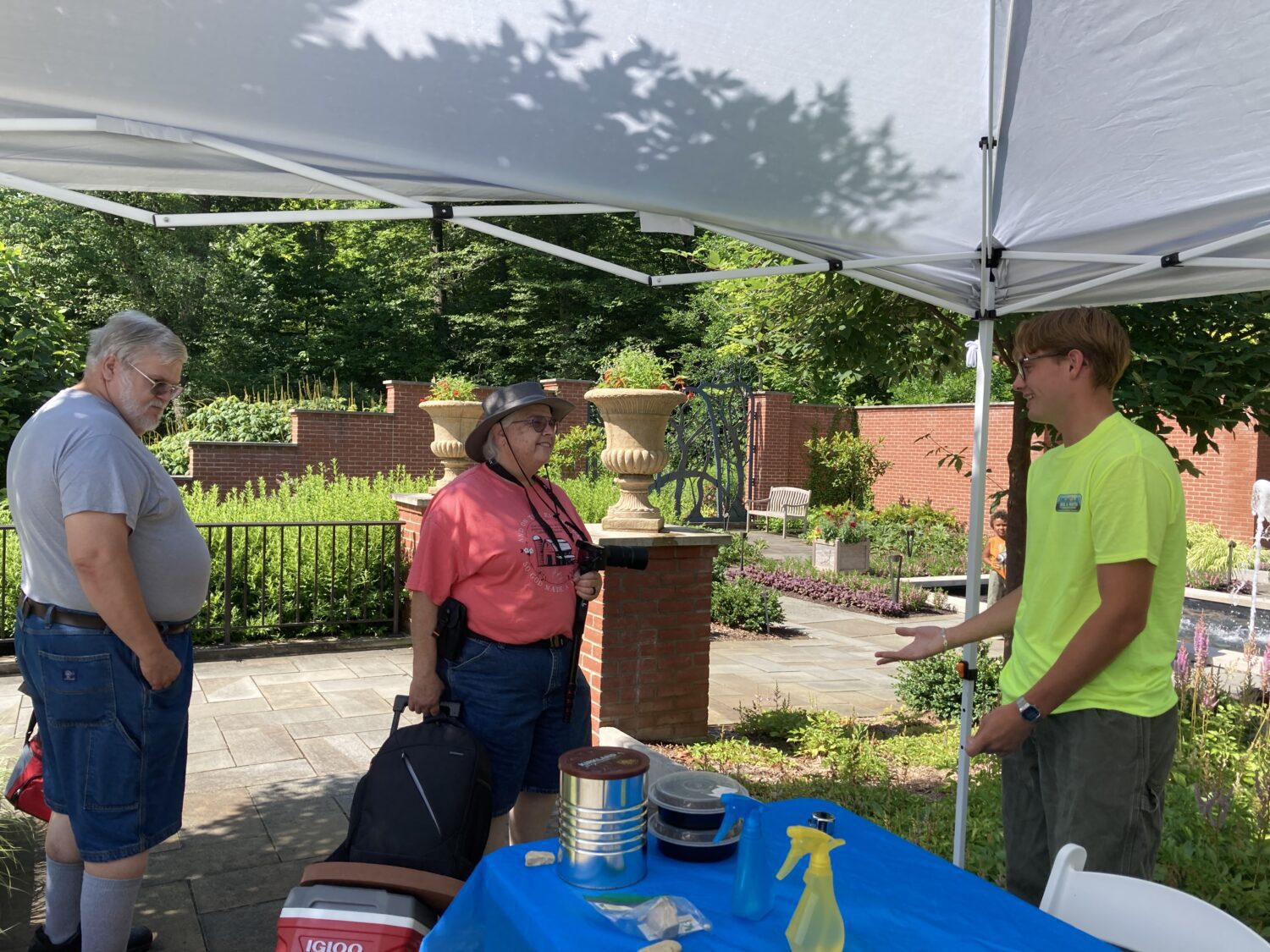 Daniel at Kingwood Center under a tent smiling and talking to two visitors.