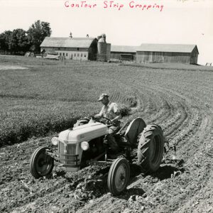 Contour strip cropping. A man plowing