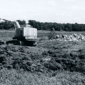 Farm crane with a bucket digging in a field