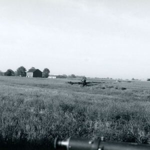 Farm field with a barn and unidentified equipment in the background