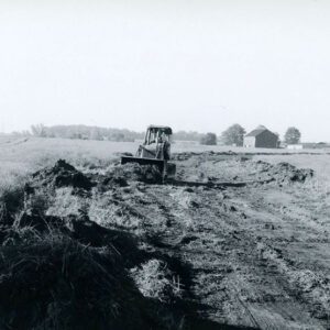 Front loader in a farm field pushing rubble