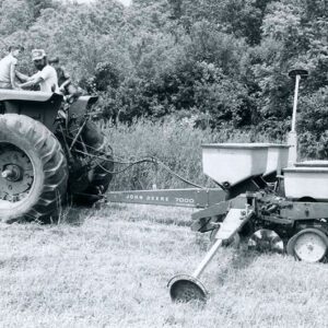 Man and two boys on a tractor pulling a seeder through a field