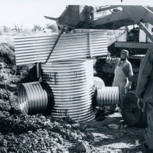 Men with Equipment Guiding Corrugated Drainage Pipe in Place