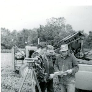 September 23, 1972 Reviewing Plans, Surveying Equipment in Foreground. Machinery in Background. Tile Drainage.