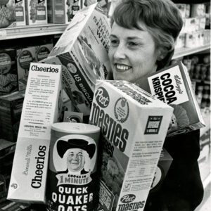 12_29_1969_Mrs._William_Zacarias_loads_arms_with_cereal_boxes_trying_to_figure_out_which_of_the_33_sizes_now_avilable_gives_her_the_most_cereal_for_her_dollar_website-2667